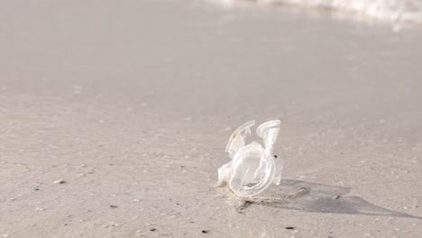 Zerdrückter-Plastikbecher,-Der-Vom-Meer-Weggespült-Wird,-Thema-Umweltverschmutzung