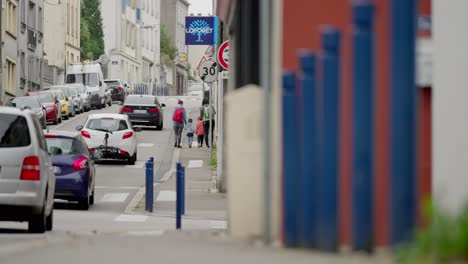 Slow-motion-scene-showing-cars-passing-and-family-walking-on-side-walk