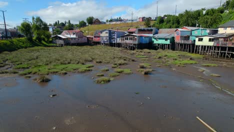 Dolly-in-establishing-a-wetland-with-low-tide-and-colorful-palafittes-in-Castro,-Chiloe,-Chile