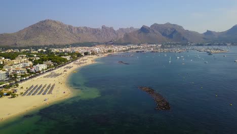 Un-Dron-Ametralló-Todo-El-Tramo-De-La-Costa-De-La-Playa-Del-Port-De-Pollença,-Un-Popular-Destino-Turístico-En-La-Isla-De-Mallorca,-España.