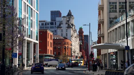 Día-Soleado-En-Manchester-Que-Muestra-La-Bulliciosa-Vida-Urbana-Con-Coches-Y-Peatones.