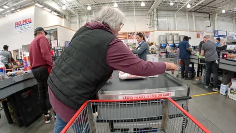 White-haired-woman-unloads-items-from-her-chart-at-Costco