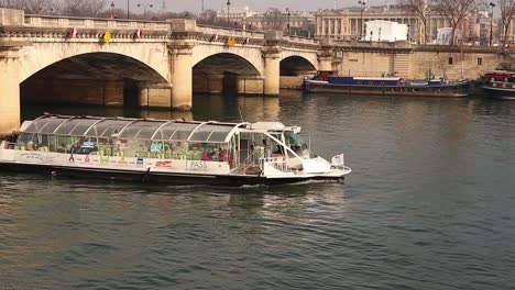 Tourist-boat-sails-on-the-Seine-passing-under-a-bridge-in-Paris-on-a-cold-winter-day