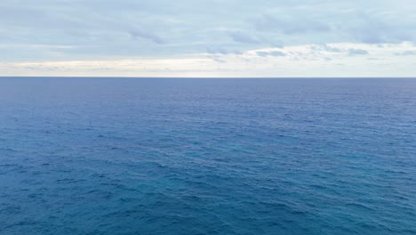 Aerial-slow-dolly-out-to-deep-blue-majestic-open-ocean-sea