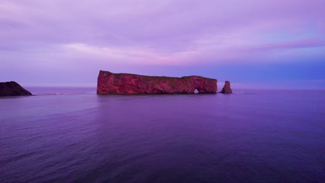 Drone-view-receding-towards-Percé-Rock-during-a-cloudy-sunset