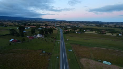 Luftdrohne-Fliegt-über-Asphaltierter-Autobahn-Durch-Grüne-Wiesenfelder-In-Chile,-Südamerikanischer-Verkehr,-Ländliche-Landschaft,-Skyline