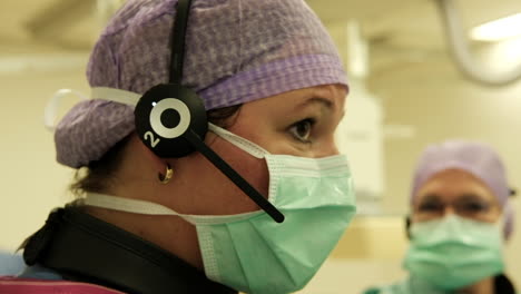 Profile-shot-of-a-woman-doctor-inside-operating-room-communicating-through-headphone-with-colleagues