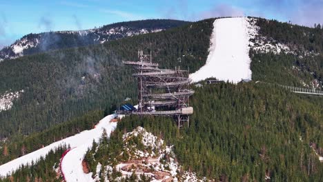 Aerial-view-of-sky-walk-attraction-and-snowy-mountain-slope,-Dolni-Morava