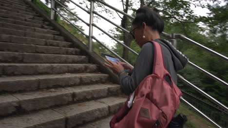 As-an-Asian-woman-ascends-the-398-steps,-she-proudly-displays-her-postcard-featuring-the-Chureito-Pagoda,-eager-to-reach-the-hilltop-overlooking-Mt