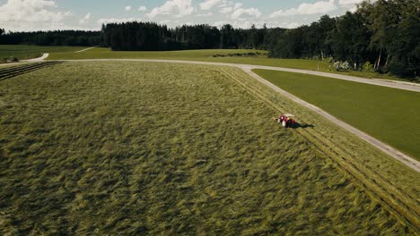 A-farmer-harvesting-crops-in-a-vast-field-on-a-sunny-day,-tractor-at-work,-aerial-view