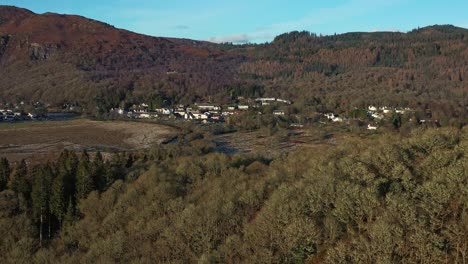 Pueblo-De-Aberfoyle-Con-El-Río-Fluyendo-Pacíficamente-A-Través-Del-Paisaje-Otoñal-Desde-Un-Dron-Aéreo