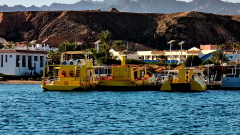 Yellow-submarine-tours-in-the-blue-waters-of-Sharm-El-Sheikh,-Egypt-with-scenic-mountains-in-the-background