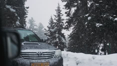 Car-Driving-Through-The-Road-During-Snowfall-In-Winter-In-Gulmarg,-Kashmiri,-India
