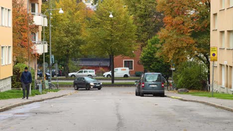 Traffic-on-Stockholm-streets-in-fall,-car-approaches-and-passes-camera