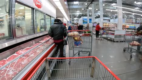 POV---Slowly-pushing-cart-past-refrigerated-cases-containing-fresh-meat-in-bulk-packaging