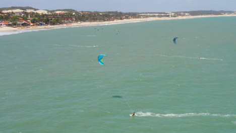 Aerial-view-of-people-practing-kite-surf-and-small-village-around,-Cumbuco,-Ceara,-Brazil
