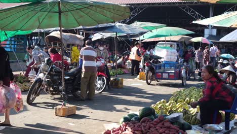 Blick-Auf-Einen-Freiluftmarkt,-Auf-Dem-Händler-Ihre-Produkte-Auf-Dem-Boden-Ausstellen,-Während-Motorräder-Und-Sonnenschirme-Der-Käufer-Die-Szene-Prägen