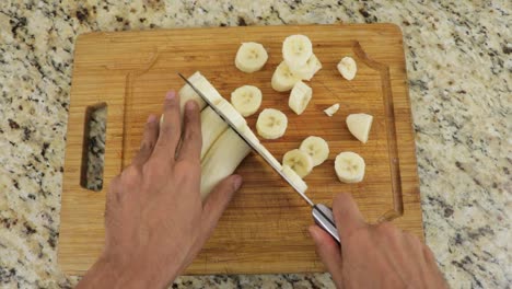 Closeup-shot-splitting-multiple-bananas-into-wheels-on-a-cutting-board