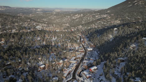 Downtown-old-historic-Evergreen-Colorado-Denver-aerial-drone-cinematic-fresh-snow-dusting-cold-white-scenic-landscape-dam-lake-traffic-driving-around-house-front-range-sunset-bluesky-backward-pan-up
