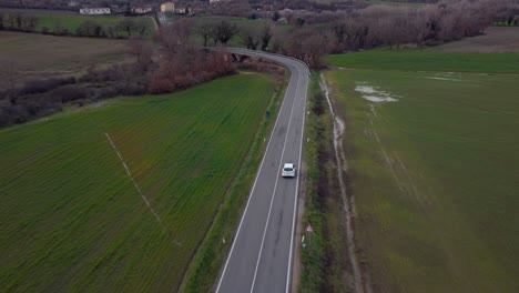 Tracking-Aerial-of-White-Car-in-a-Italian-Road,-Tuscany,-Italy