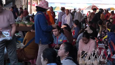 Eine-Lebhafte-Versammlung-Laotischer-Menschen,-Die-Eng-Beieinander-Im-Erdgeschoss-Sitzen-Und-Ihre-Produkte-Auf-Dem-Dao-Heuang-Markt-Verkaufen