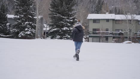 Back-View-of-Teenage-Girl-Running-in-Snow,-Slow-Motion