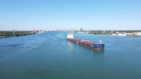 Freighter-steaming-down-the-Detroit-River,-with-the-Detroit-City-skyline-in-the-background