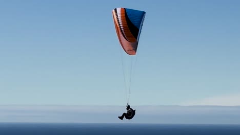 Single-para-glider,-flying-close-up-along-the-ocean-on-a-beautiful-sunny-day-at-Torrey-Pines-Gliderport-in-La-Jolla,-California