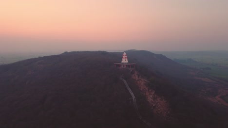 Luftaufnahme-Eines-Hindutempels-Auf-Einem-Hügel-Mit-Treppen,-Die-Während-Des-Sonnenuntergangs-In-Einem-Dorf-In-Gwalior-In-Madhya-Pradesh,-Indien,-Dorthin-Führen