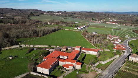 Drone-Orbita-Alrededor-De-Un-Monasterio-Ubicado-Entre-Grandes-Campos-De-Cultivo-Abiertos-En-Ourense,-España