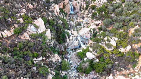 Luftaufnahme-Eines-Wasserfalls-Mit-Graffiti-Und-Markierten-Felsen-Drumherum