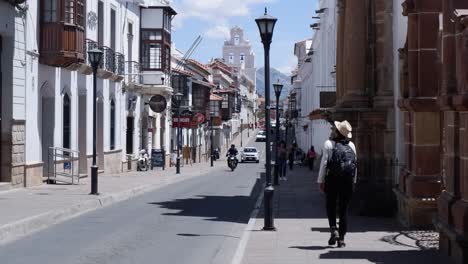 Woman-walks-on-narrow-city-street-toward-cathedral-in-Sucre,-Bolivia
