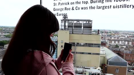 Mujer-Filmando-Dublín-A-Través-De-Una-Gran-Ventana-En-Un-Mirador,-Irlanda