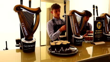 Young-male-waiters-serving-beers-for-visitors-to-taste-at-Guinness-Storehouse,-Dublin