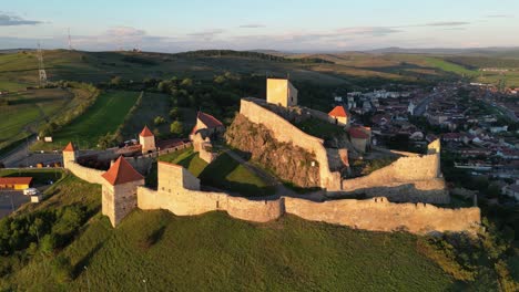 Castillo-Fortaleza-En-La-Cima-De-Una-Colina-En-Rupea,-Transilvania,-Rumania---Círculos-Aéreos-4k