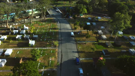 Drone-Inclinándose-Sobre-Una-Carretera-En-Medio-De-Tumbas-En-El-Parque-Conmemorativo-De-Manila,-Filipinas