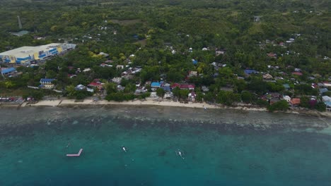 Oslob-town-in-cebu-island-with-mist-over-the-lush-landscape-and-local-buildings,-aerial-view