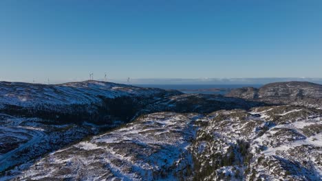 Forested-Mountain-Ridge-Snow-Covered-With-Wind-Turbines-In-The-Background-Near-Bessaker,-Norway