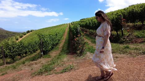 Mujer-Vestida-Caminando-En-Un-Viñedo-En-Constantia,-Ciudad-Del-Cabo,-Sudáfrica---Toma-De-Seguimiento