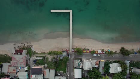 Aerial-footage-of-wooden-dock-in-a-small-Saint-Lucian-village,-Caribbean,-West-Indies