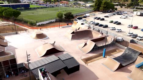 Aerial-establishing-shot-of-people-biking-on-the-ramps-at-a-skatepark