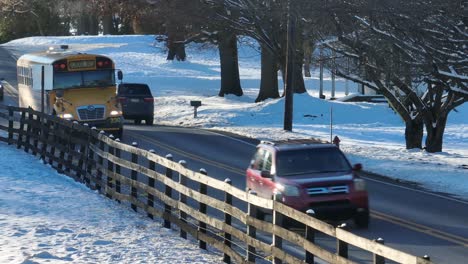 Yellow-school-buses-driving-on-road-past-snow-covered-landscape-on-way-to-school-in-USA