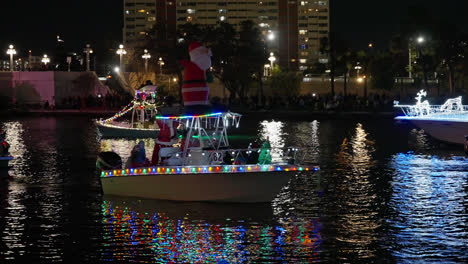 Lots-of-People-on-Boats-Decorated-with-Bright-and-Colorful-Lights-having-fun-in-a-Christmas-Boat-Parade-in-Tampa-Florida,-Static-Shot