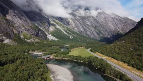 Aerial-footage-showing-the-Rauma-river-in-Norway,-with-mountains,-greenery-and-grass
