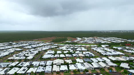 Drone-Aéreo-De-Un-Suburbio-Residencial-Con-Techos-Grises-Blancos-En-Un-Día-Tormentoso-En-El-Territorio-Norteño-De-Zuccoli,-Australia,-Visión-Panorámica