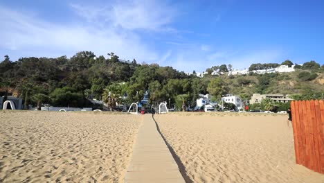 Wooden-boardwalk-leading-to-the-sunny-Sidi-Bou-Said-beach-in-Tunisia,-clear-blue-sky