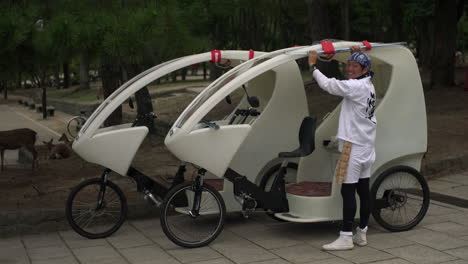 Near-the-Toda-ji-temple-in-Nara,-Japan,-a-modern-white-three-wheeled-manual-bike,-intended-for-tourists,-is-operated-by-a-Japanese-driver