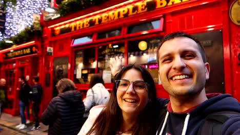 Selfie-De-Pareja-Sonriente-Con-El-Vibrante-Pub-Temple-Bar-Al-Fondo,-Dublín