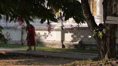 Monk-in-orange-robe-cleaning-temple-grounds-during-golden-hour