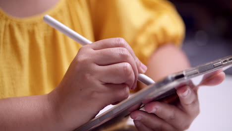 Woman-in-yellow-dress-using-pen-on-tablet-to-draw